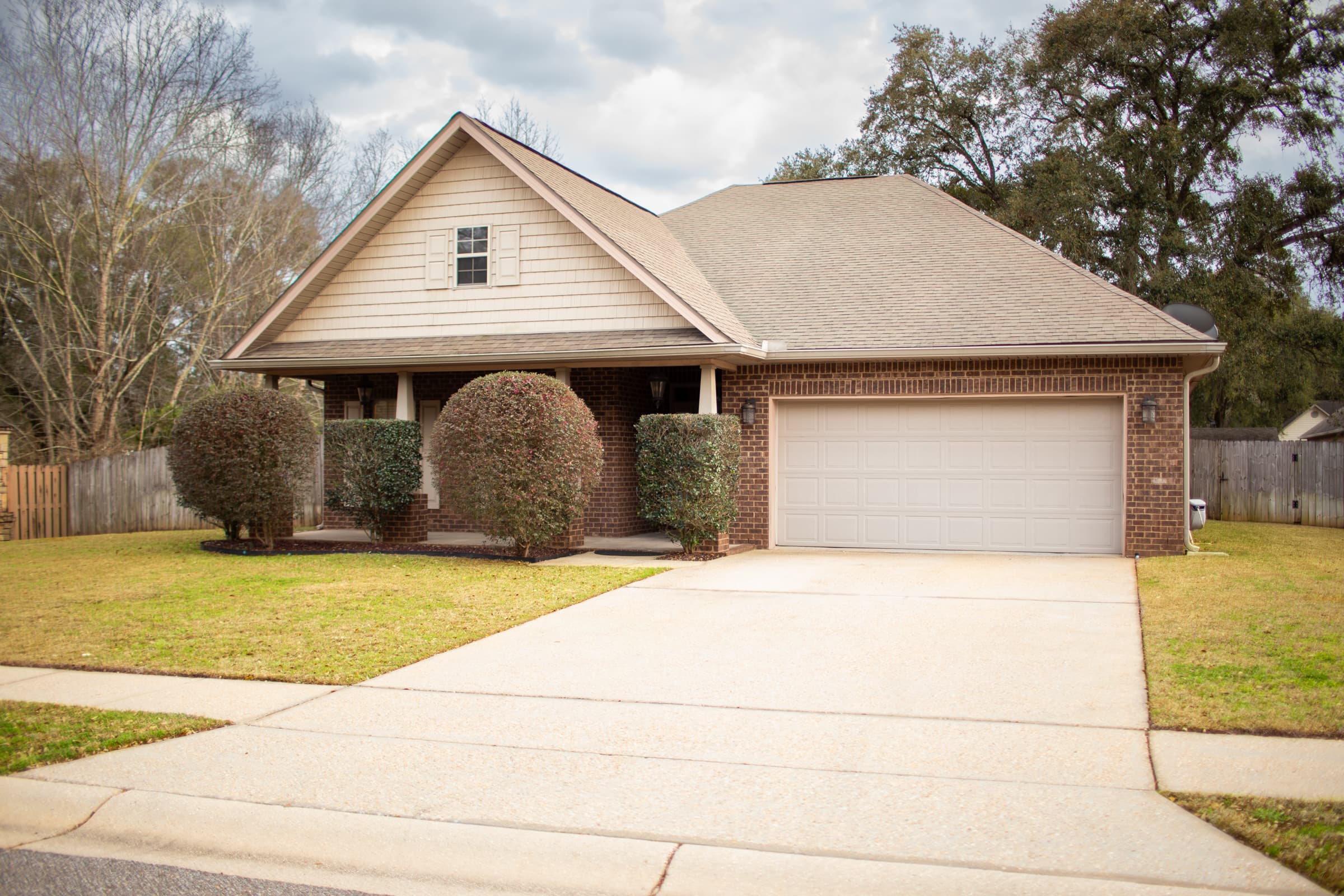 Front exterior of home with brick and siding, covered porch, and 2-car garage
