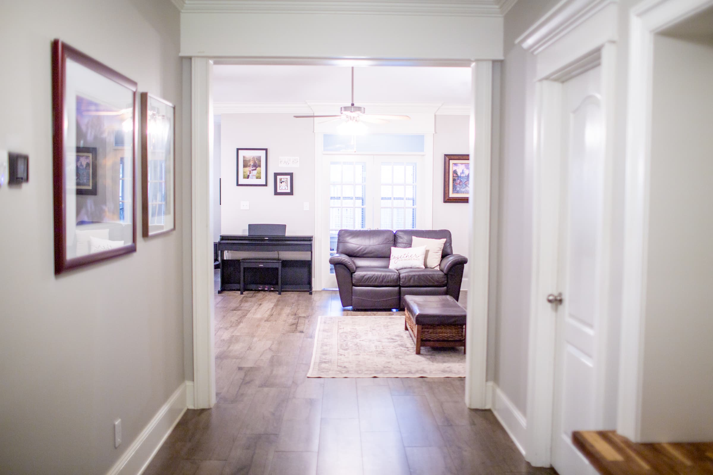 Hallway view into sunroom with piano and seating
