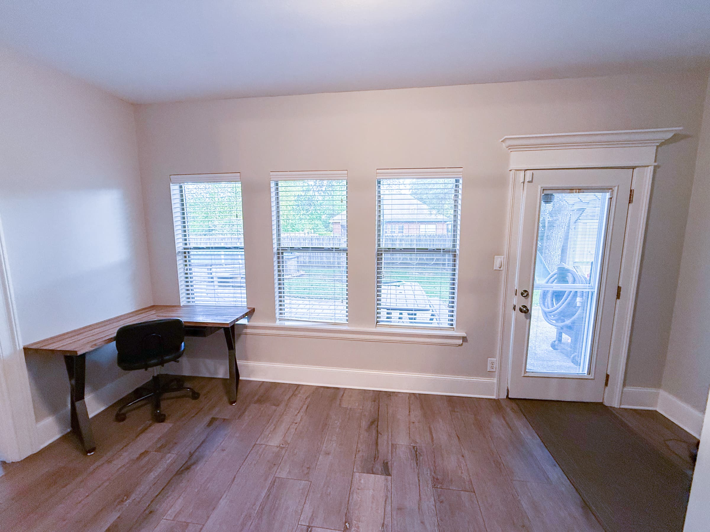 Sunroom office space with desk and backyard door